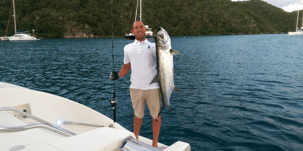 Fisherman holding a large Tarpon on back of yacht